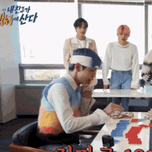 a man wearing a headband is sitting at a table with korean writing on the wall behind him