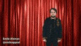 a man standing in front of a red curtain with the name emile aleman written below him