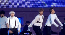a group of young men are dancing on a stage in front of a screen .