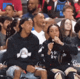 a group of people are sitting in a stadium wearing atl dream team shirts