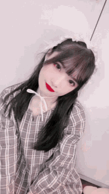 a girl wearing a plaid dress and red lipstick