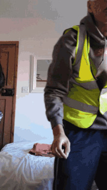 a man wearing a yellow vest is standing in a room
