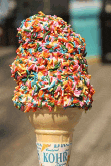 a kohr ice cream cone filled with rainbow colored sprinkles