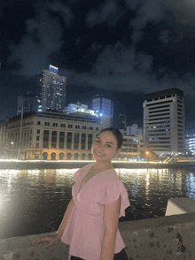 a woman in a pink top stands in front of a large building that says ' allianz ' on it