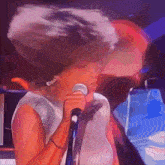 a woman singing into a microphone with her hair blowing