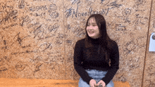 a woman sits on a bench in front of a wall that says novel bright