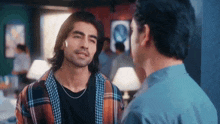two men are standing next to each other in a room and talking .
