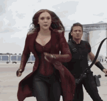 a woman in a red coat is running next to a man in a black shirt