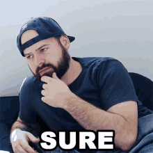 a man with a beard wearing a hat and a t-shirt that says sure on it