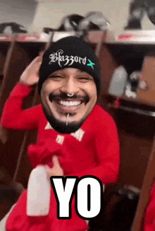 a man with a beard wearing a black beanie and a red shirt is smiling and saying yo