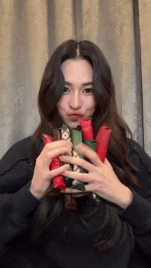 a woman in a black shirt is holding a bunch of wrapped candy