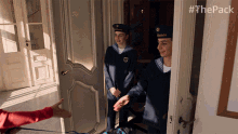 two men in uniform are standing in a doorway with #thepack written on the bottom right