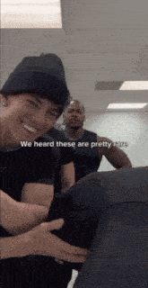 a man wearing a beanie is holding another man 's butt while another man looks on .