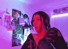 a woman in a black jacket is standing in front of a purple wall .