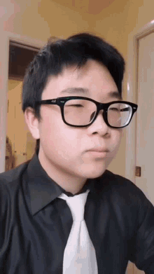 a young man wearing glasses and a black shirt looks at the camera