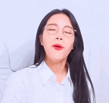 a woman wearing glasses and red lipstick is holding a piece of paper with a foreign language written on it .