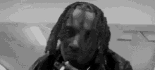 a black and white photo of a man smoking a cigarette in a room .