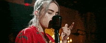 a woman in a red shirt is singing into a microphone