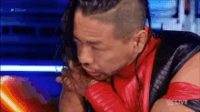 a man in a red and black outfit is sitting in front of a blue screen .
