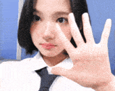 a woman wearing a white shirt and tie holds her hand up to her face