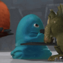 a blue cartoon character is sitting at a table
