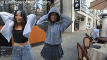 a couple of girls are standing next to each other on a city street .