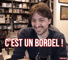a man sitting in front of a microphone with the words c est un bordel