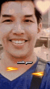 a man in a blue shirt smiles with the words smile your written on his neck