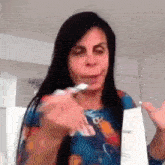 a woman with long black hair is holding a piece of paper in front of her face .
