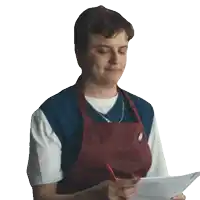 a man in an apron is writing on a piece of paper with a pen
