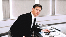 a man in a suit and tie is sitting at a table with papers on it