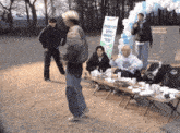 a group of people are gathered around a table with a sign that says ' premium camping day ' on it