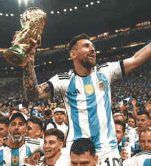 a soccer player holds up a trophy in front of a crowd of fans