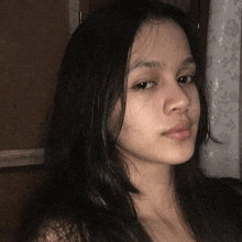 a young woman with long dark hair is looking at the camera