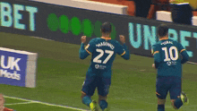 a soccer player wearing a number 27 jersey celebrates a goal