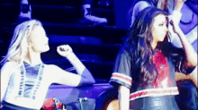 two women are standing next to each other on a stage in a stadium .