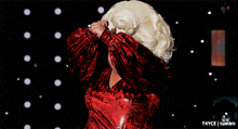 a drag queen in a red velvet dress is dancing with her hands in the air