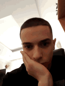 a close up of a man 's face with a hand on his chin