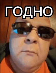 a man wearing sunglasses and an orange shirt has a foreign language written on his face