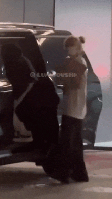 a woman wearing a mask is getting out of a black suv