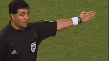 a referee wearing a black adidas shirt with a fifa logo on it