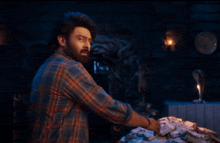 a man in a plaid shirt is looking at a pile of money