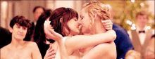 a bride and groom are kissing at their wedding reception while hugging each other .