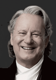 a man with gray hair is smiling and wearing a black jacket