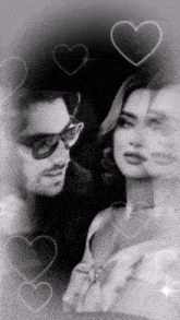 a black and white photo of a man and a woman with hearts surrounding them