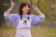 a woman wearing a striped sweater and overalls with the word magore on it