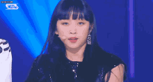 a woman is standing in front of a microphone on a stage and singing into it .