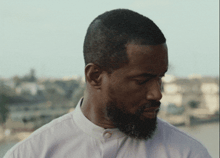 a man with a beard and a white shirt is looking down