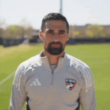a man with a beard is wearing an adidas jacket