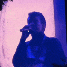a man is singing into a microphone in front of a blue screen .